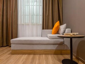 Una habitación moderna con un sofá, una mesita redonda y una ventana con cortinas.