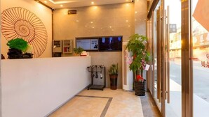 A hotel reception area with a modern design, including a large wall art piece, a reception desk, a television screen, and potted plants. - Shell Jiangsu Kunshan Development Zone Wusongjiang South Road Hotel (Suzhou)