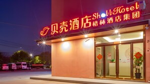 A hotel entrance with a neon sign, glass doors, and a small plant near the entrance. - Shell Jiangsu Kunshan Development Zone Wusongjiang South Road Hotel (Suzhou)