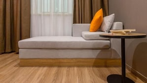 A modern living room with a sofa, a round table, and a window with curtains. - Shell Jiangsu Kunshan Development Zone Wusongjiang South Road Hotel (Suzhou)