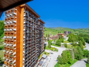 Korkea hotellirakennus, jossa on useita parvekkeita ja näkymä vehreään laaksoon.