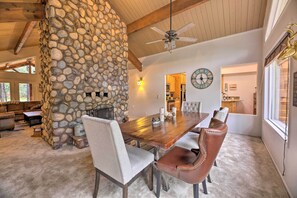 A dining area with a stone wall, wooden ceiling beams, a chandelier, and a clock on the wall. - Wooded Yard, Gas Grill: Lush Pinetop Retreat (Pinetop)