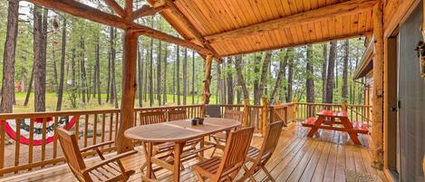 Una terraza de madera con una mesa y sillas, con vista a un bosque.