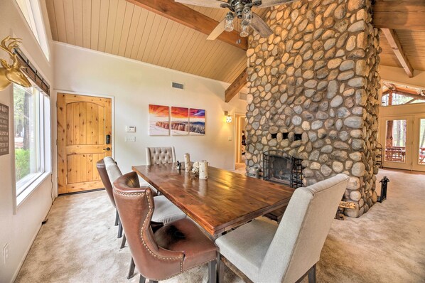A dining area with a wooden table and chairs, a stone fireplace, and a wooden ceiling. - Wooded Yard, Gas Grill: Lush Pinetop Retreat (Pinetop)
