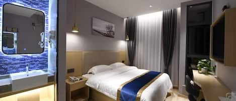 Une chambre d’hôtel moderne avec un grand lit, une table de chevet et un bureau intégré avec une chaise.