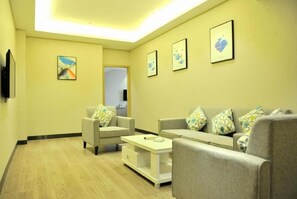 A living room with a sofa set, a coffee table, and artwork on the walls. - Echarm Hotel Hefei Binhu Exhibition Center (Hefei)