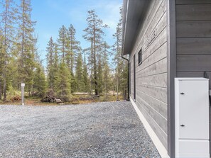 A building with a gravel driveway and a forested area in the background.
