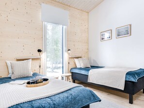 A modern bedroom with two beds, a large window, and a view of the outdoors.