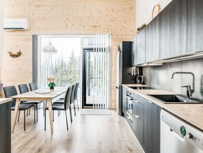 A modern kitchen with a built-in oven, a sink, and a dining area with a table and chairs.