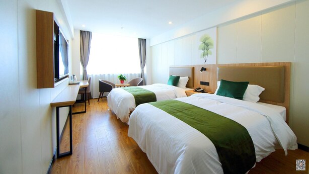 Ein Hotelzimmer mit zwei Betten, einem Schreibtisch, einem Stuhl und einem fenster mit Vorhängen.