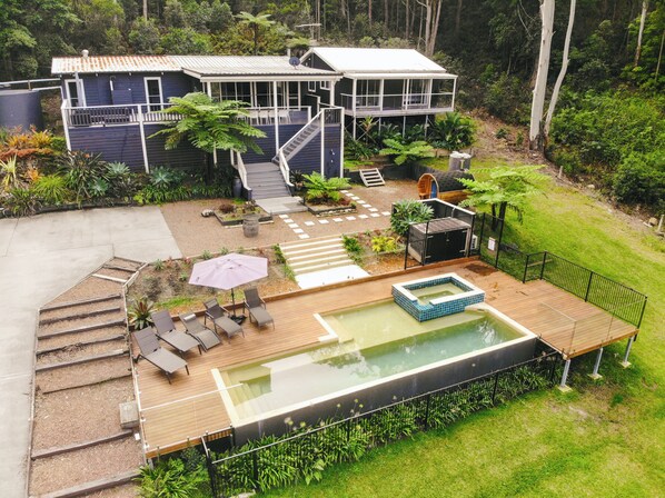 A house with a swimming pool, outdoor seating, and a staircase leading to the upper level. - Bellavia Forest Retreat with pool and spa. Minutes to lake and beaches! (Whoota)