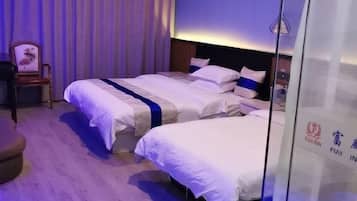A hotel room with two beds, a wooden floor, a curtain, and a wall with a logo.