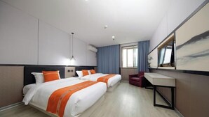 Une chambre d’hôtel avec deux lits, un bureau, une chaise et un grand miroir.