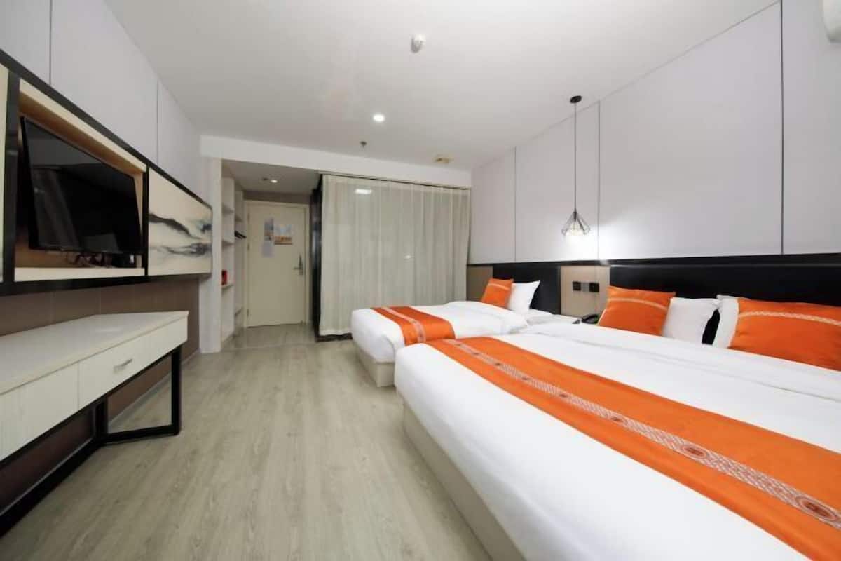 A hotel room with a large bed, a desk, a TV, and a wardrobe.