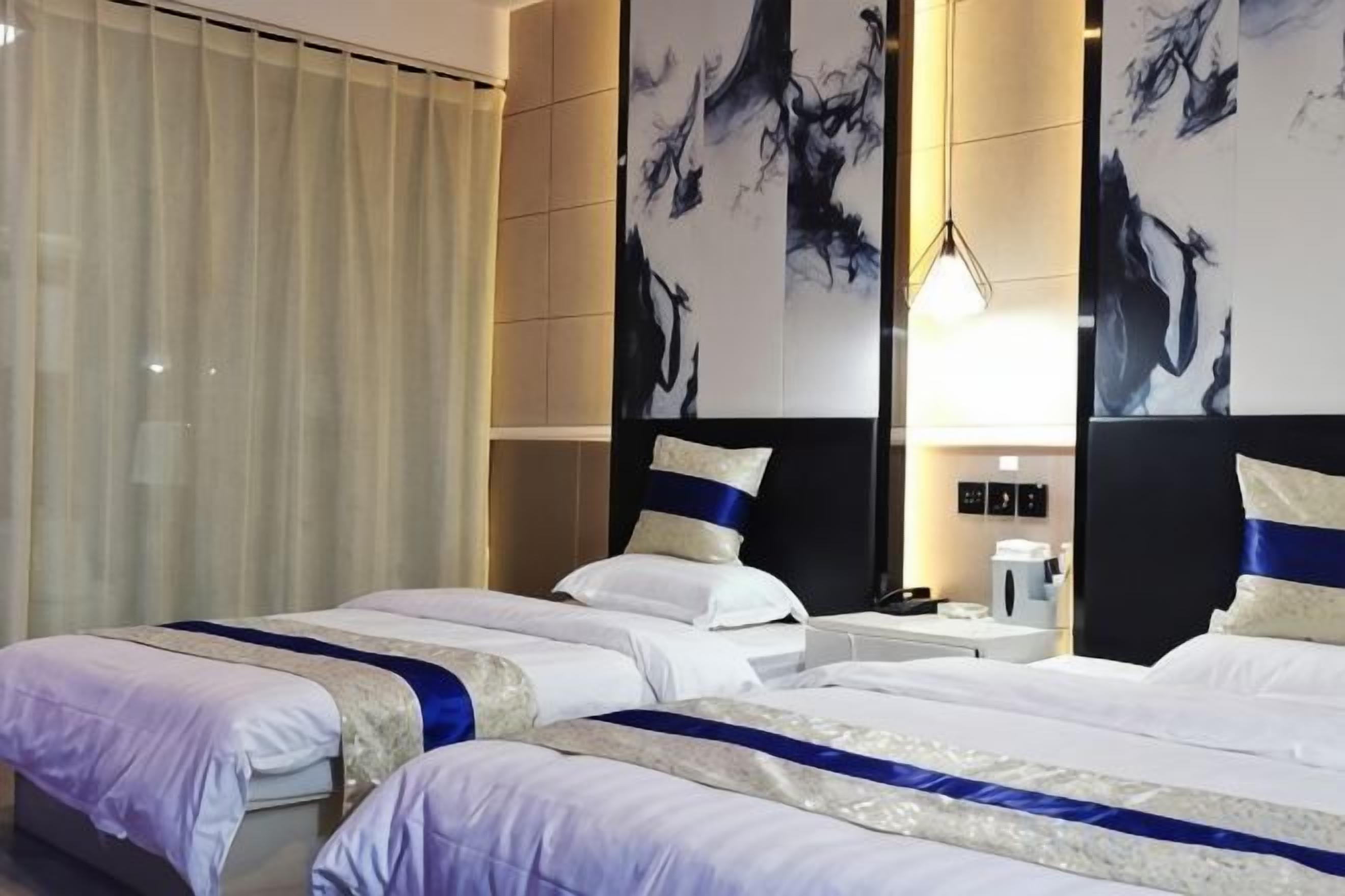 Habitación de hotel con dos camas, un espejo grande y obras de arte en las paredes.