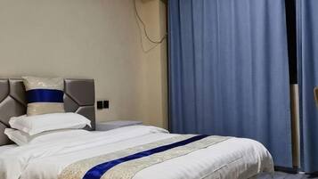 A hotel room with a bed, a headboard, a window with curtains, and a wall-mounted air conditioner.