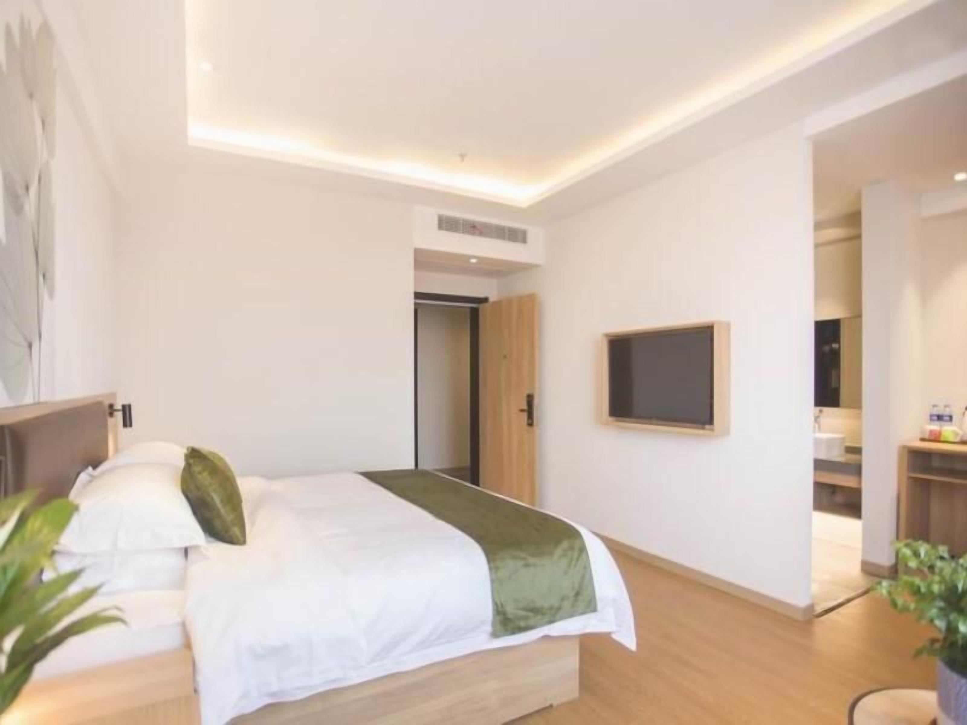 A hotel room with a bed, a television, and a door leading to a bathroom.