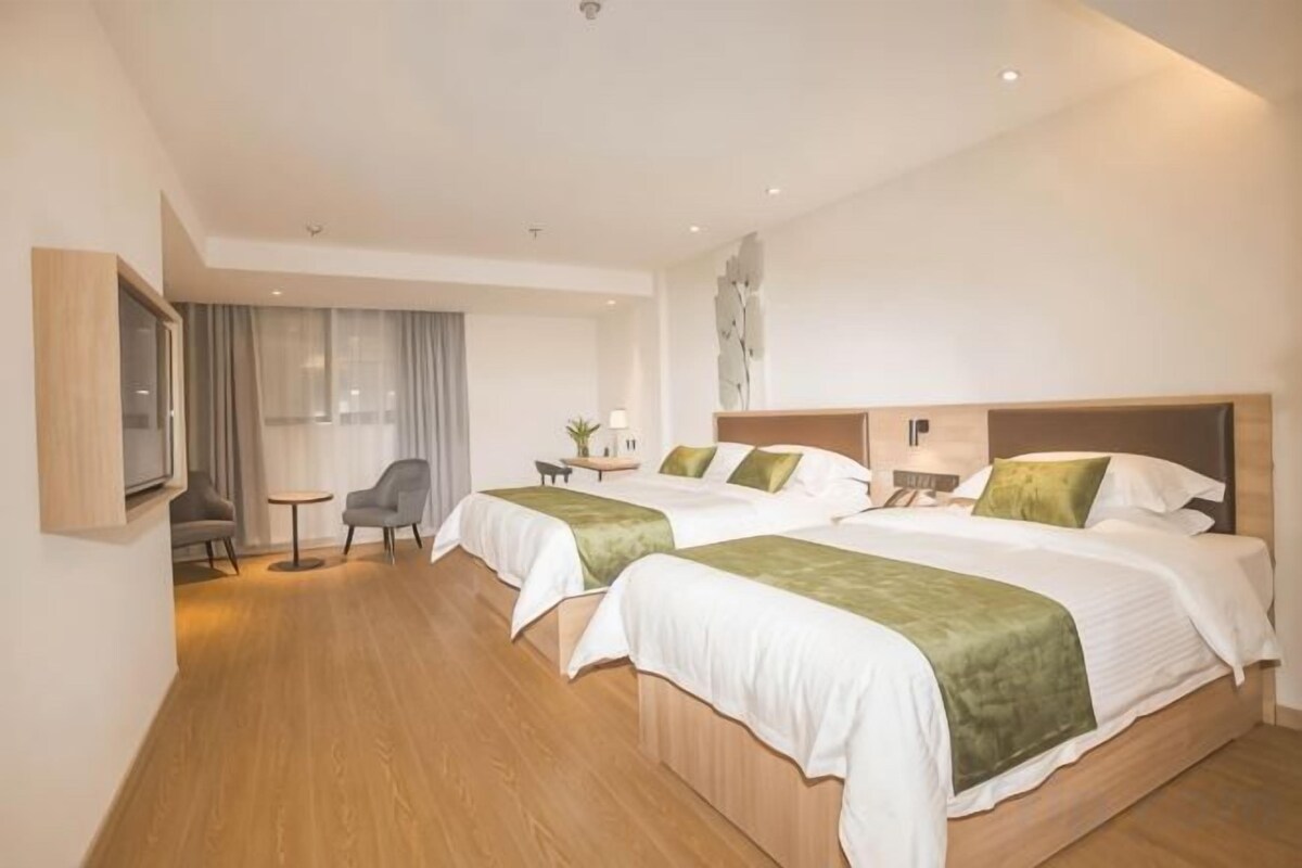 Ein Hotelzimmer mit zwei Betten, einem Schreibtisch, einem Stuhl und einem Fernseher.