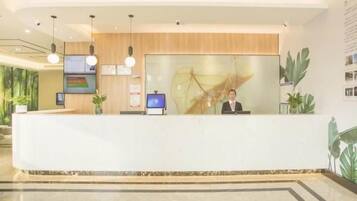 A modern reception desk with a digital screen, wooden paneling, and a large abstract painting.