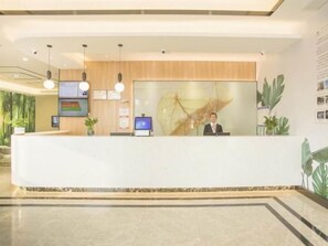 A modern reception desk with a digital screen, wooden paneling, and a large abstract painting. - Greentree Inn Taizhou Jiangyan Hardware City Expre (Taizhou)