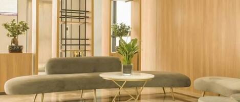 A modern lobby with a grey sofa, a small round table, and a potted plant.