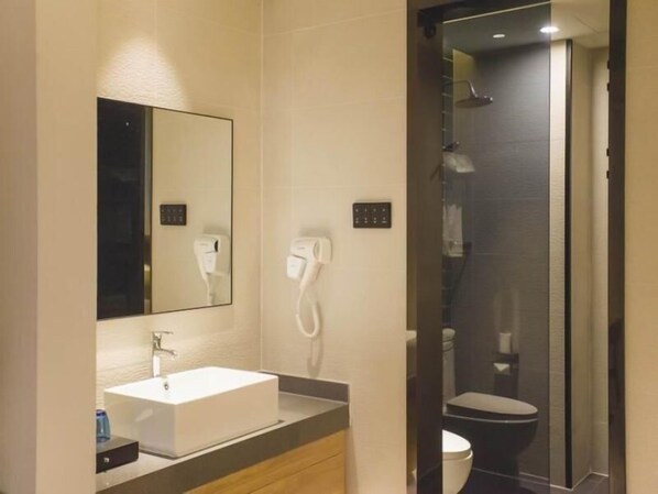 Un baño moderno con un lavabo blanco, un espejo, un secador de pelo y un inodoro.