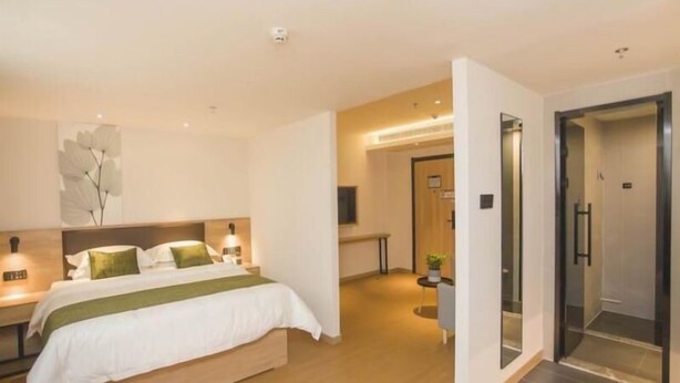 A modern hotel room with a large bed, bedside tables, a wall-mounted TV, and a separate bathroom area. - Greentree Inn Taizhou Jiangyan Hardware City Expre (Taizhou)