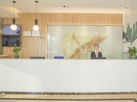 A reception desk with a large abstract artwork on the wall, a computer, and a potted plant.