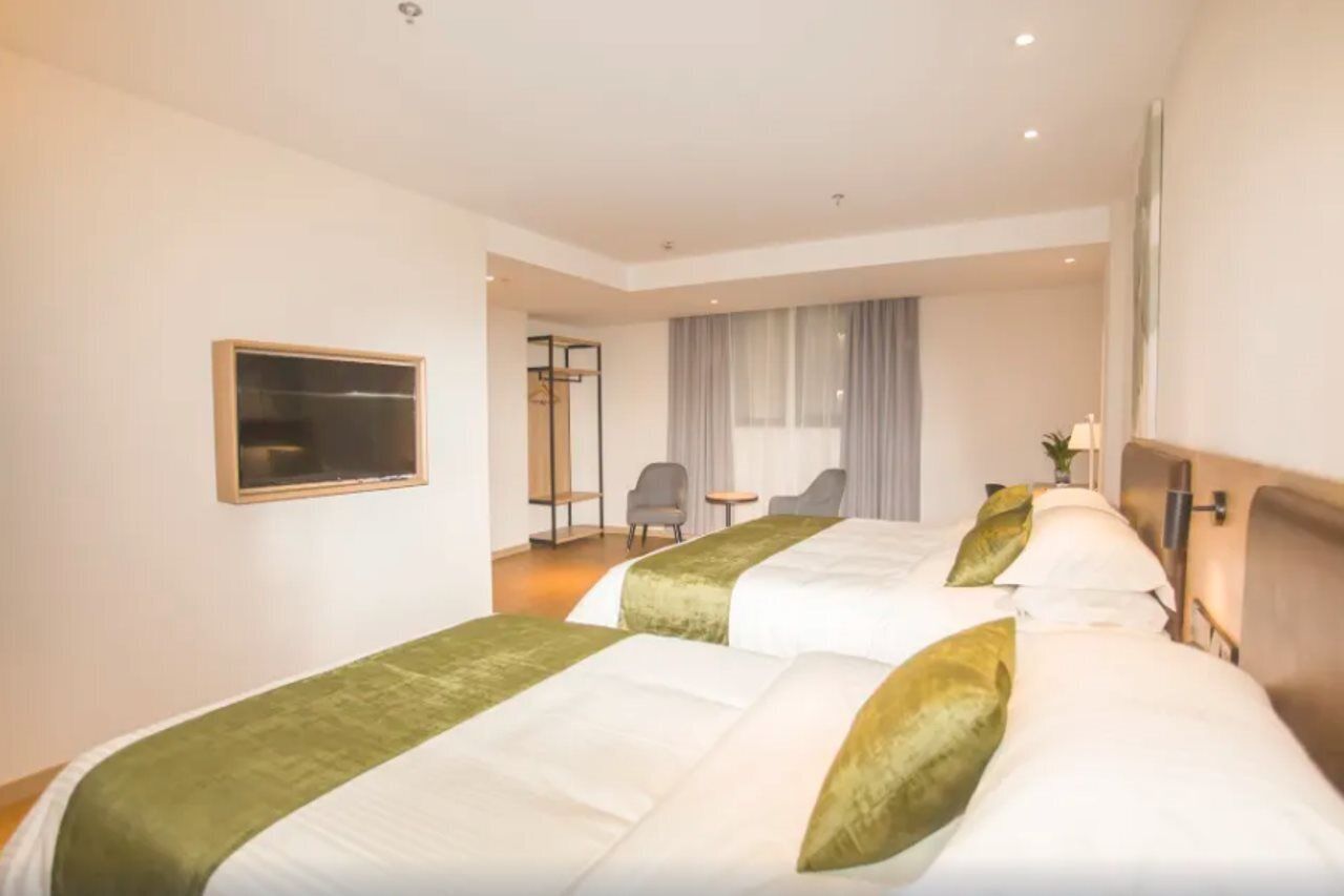 A hotel room with two beds, a desk, and a chair.