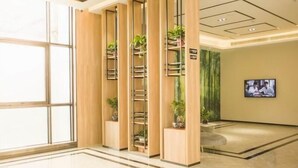 A modern hotel lobby with a large open space, wooden paneling, and a television screen on the wall. - Greentree Inn Taizhou Jiangyan Hardware City Expre (Taizhou)