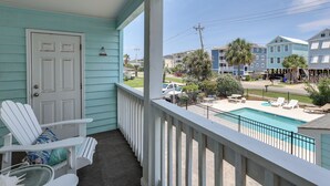 Un balcon donnant sur une piscine, une porte et une chaise.