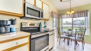 A kitchen with a microwave, oven, coffee maker, and dining area with chairs and a table. - Disney Launchpad for Families! Private Pool (Kissimmee)