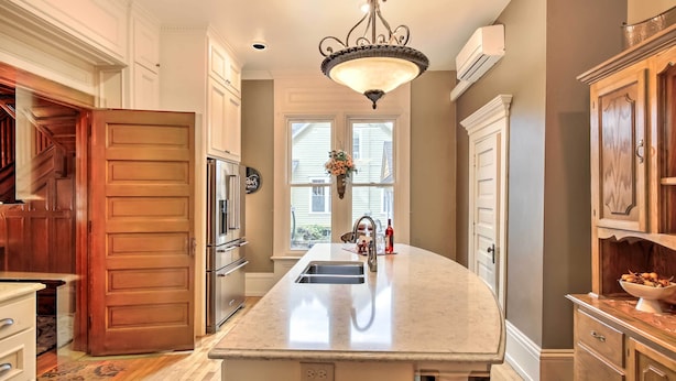 A kitchen with a large island, wooden cabinets, a chandelier, and a view through the windows. - Free WiFi Home w/ Balcony & Yard in Surgeon Bay (Sturgeon Bay)