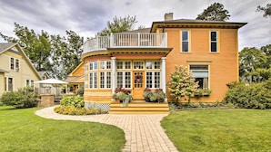 A two-story house with a curved front, a balcony, and a front porch with potted plants. - Free WiFi Home w/ Balcony & Yard in Surgeon Bay (Sturgeon Bay)