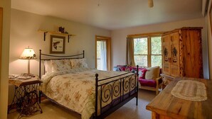 Une chambre à coucher avec un lit, une table de chevet, une lampe et une armoire en bois.