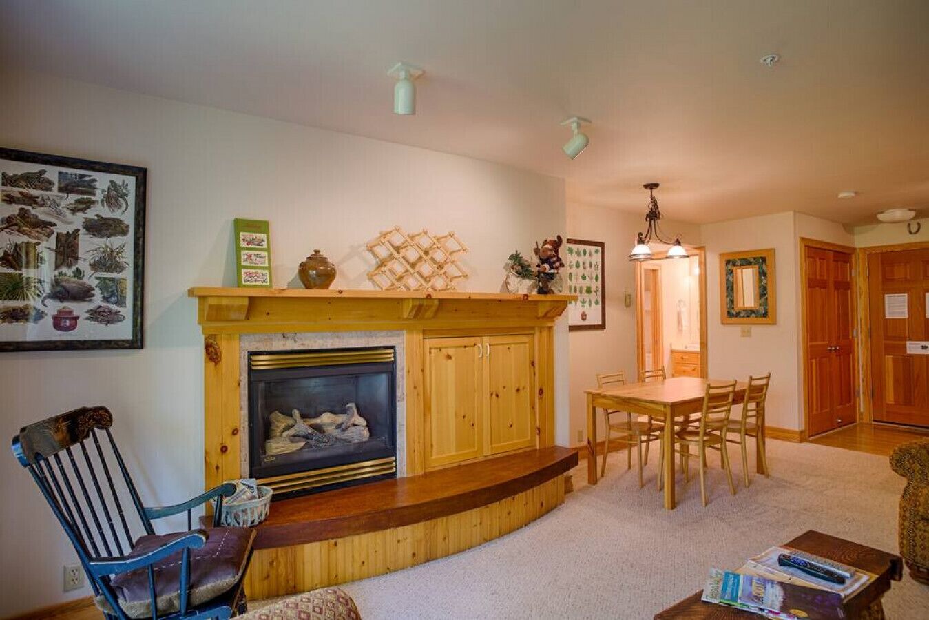 A cozy living room with a fireplace, wooden furniture, and a dining area.
