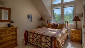 Camera da letto con un letto, una cassettiera in legno, comodini e un'ampia finestra con vista.