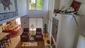 Un'ampia zona giorno con soffitto alto, un tavolo da pranzo, divani in pelle, un tavolino da caffè e un camino.