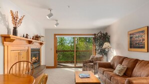 A living room with a fireplace, a sofa, a coffee table, and a dining area with chairs.