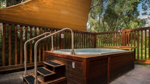 A hot tub with wooden steps and railings, surrounded by a wooden deck and trees. - Grizzly Bear Den: Near Targhee, Sleeps 6, Hot Tub (Driggs)