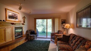A cozy living room with a fireplace, a large window, and a sofa. - Grizzly Bear Den: Near Targhee, Sleeps 6, Hot Tub (Driggs)