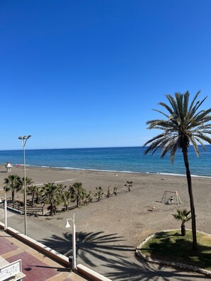 Una playa con palmeras, cielo despejado y el océano.