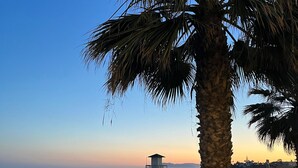 A beach with a lifeguard tower, palm trees, and a clear sky. - Apartment "Studio 2 Sea front" At the Beach with Sea View (Rincón de la Victoria)