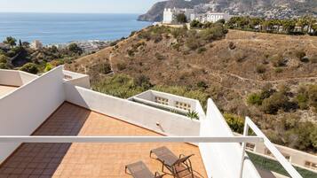 Eine Dachterrasse mit Blick auf das Meer und einen Hügel mit Gebäuden.