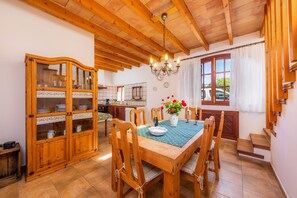Un espace repas avec des meubles en bois, un lustre et une vue sur l’extérieur.