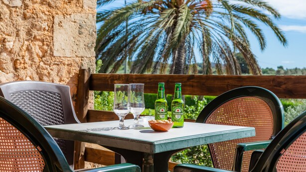 A table with two Heineken beer bottles, two glasses, and a bowl of snacks. - Vacation Home 'Cas Casai' with Mountain View, Pool & Wi-Fi (Son Negre)