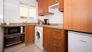 Una cocina compacta con electrodomésticos integrados, armarios de madera y un refrigerador Corbero.