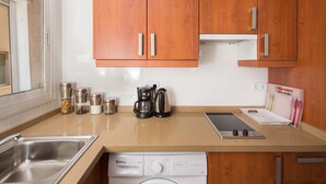 Una cocina con armarios de madera, lavavajillas, cafetera y una tablet sobre la encimera.