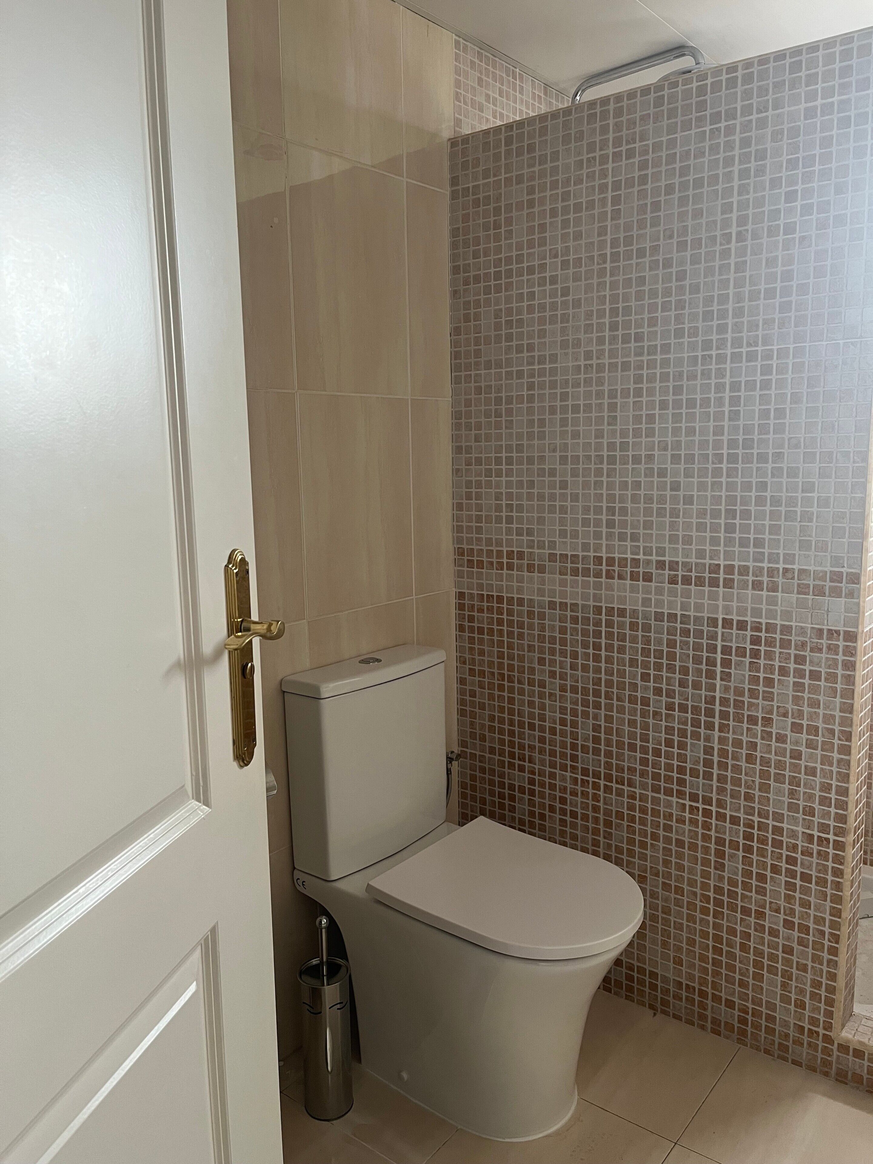 Une salle de bain équipée de toilettes, d’une poubelle et d’un espace douche.