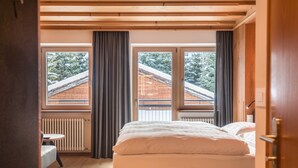 Un dormitorio con cama, ventana, radiador y una pequeña mesa.